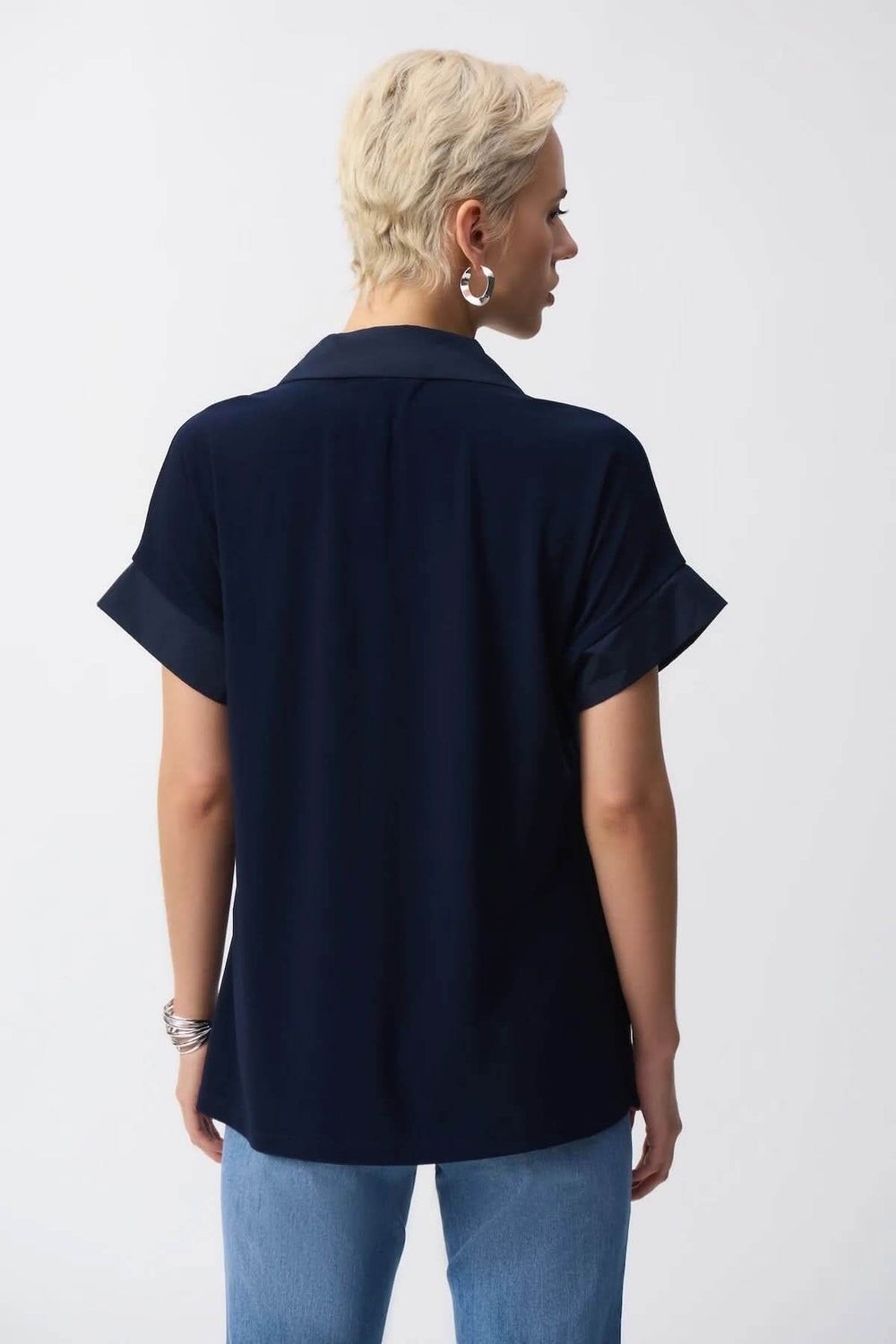 Back view of a navy blue short-sleeve blouse with a collar and dolman sleeves.