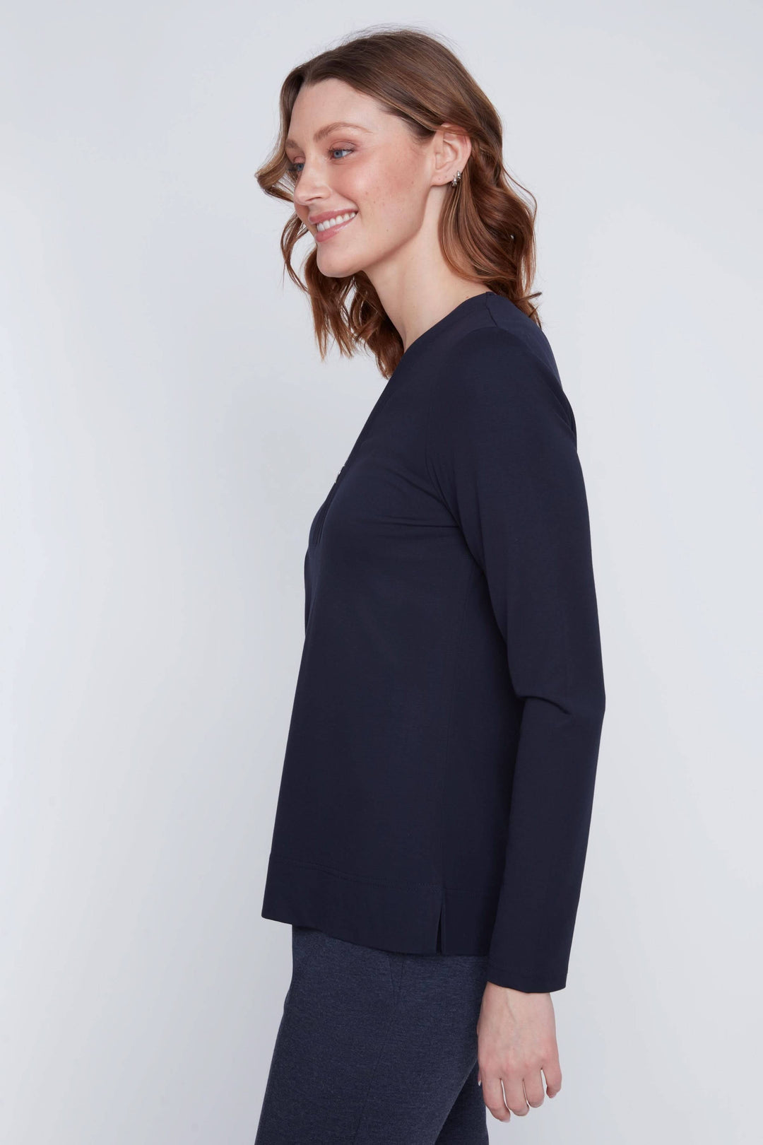 Femme portant un chandail encolure en V zippée, manches longues, coupe droite noire, style minimaliste et moderne.