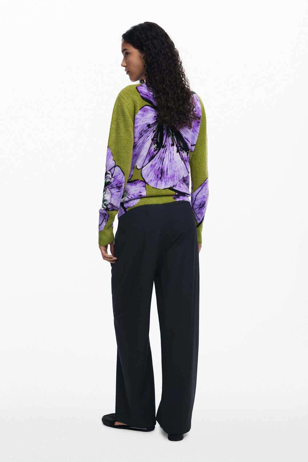 Chandail floral à col rond avec imprimé oversize, arboré par une femme de dos portant un pantalon noir chic.