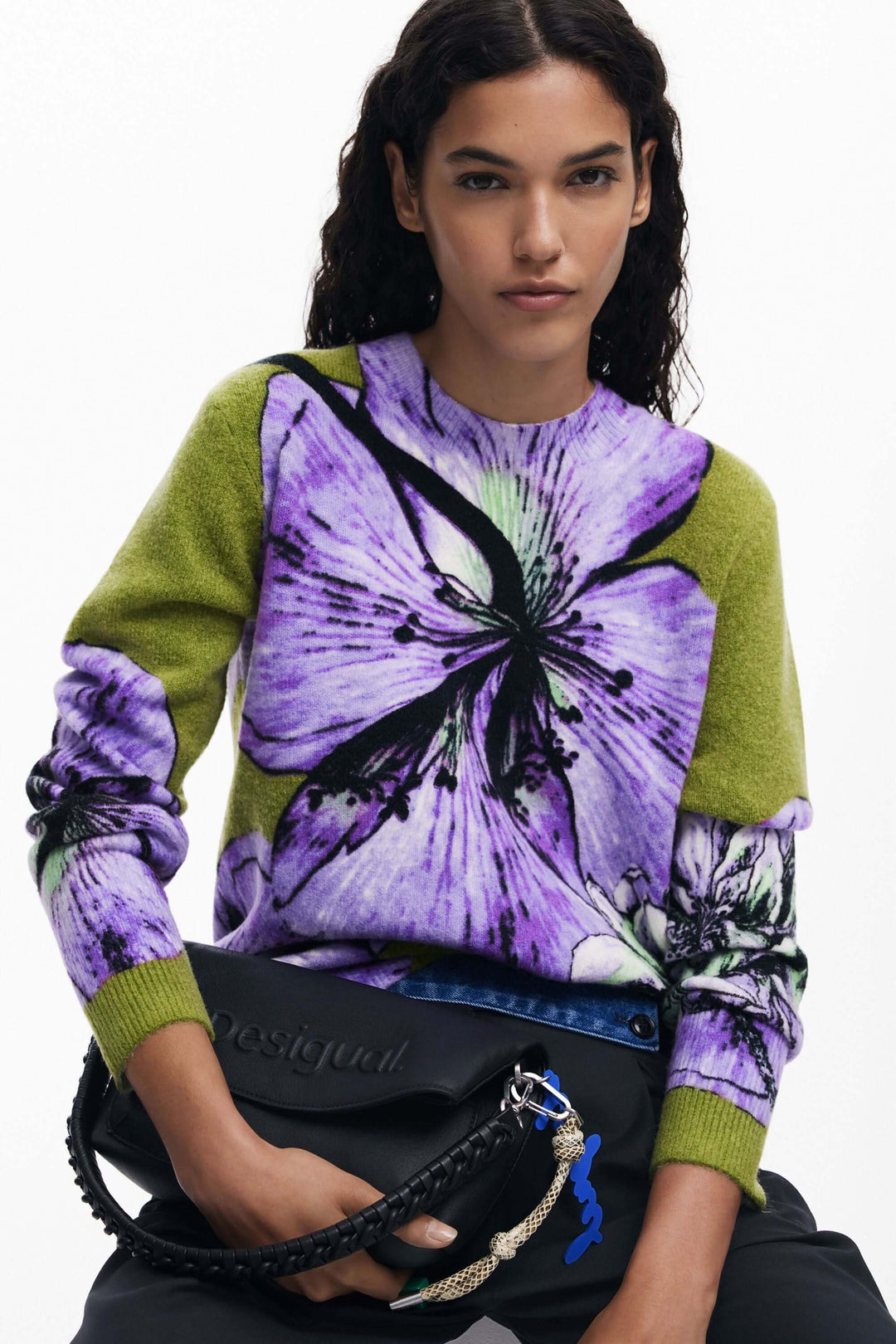 Chandail floral avec imprimé oversize violet et vert, porté par une femme, style décontracté et artistique.