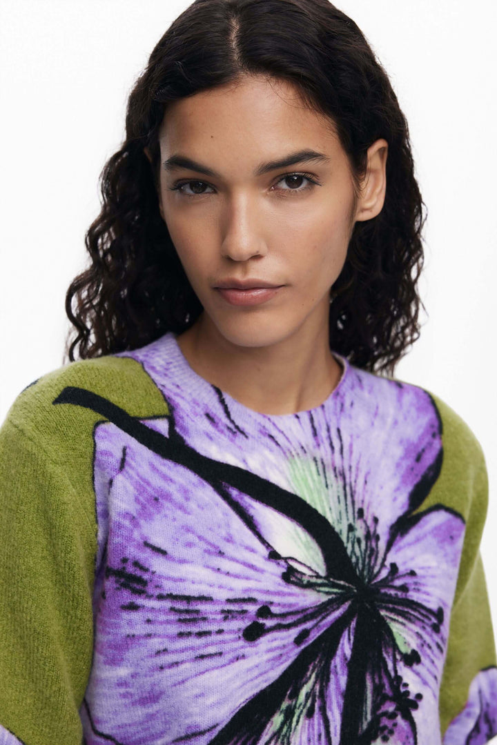Femme portant un chandail floral violet et vert avec imprimé floral oversize, col rond classique. Chandail floral mode élégante.
