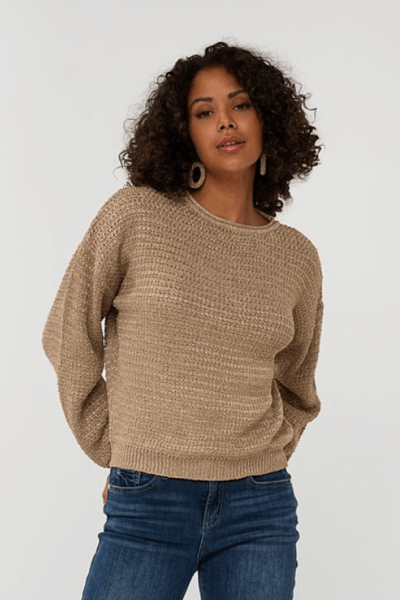 Femme portant un chandail gaufrée beige avec une coupe ample et manches longues, look casual avec jean ajusté.