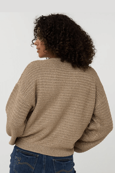 Femme portant un chandail gaufrée beige de dos, avec manches longues et encolure ronde, style décontracté et chic.