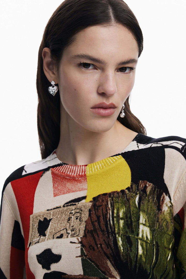 Femme portant un chandail imprimé artistique avec un col rond et des boucles d'oreilles brillantes.