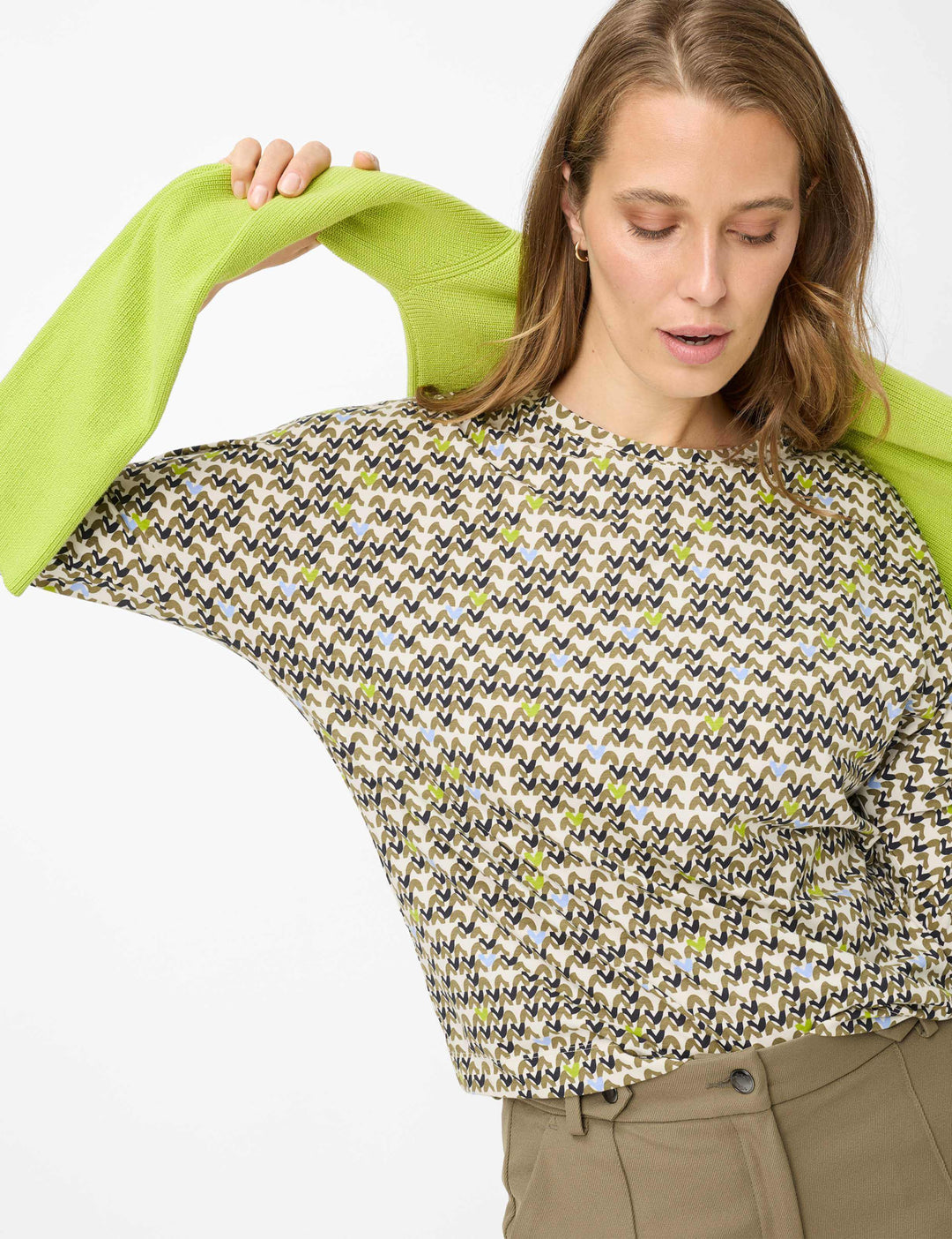 Femme portant un Chandail imprimé graphique CHARLENE avec manches trois-quarts et encolure ronde, style moderne et énergique.