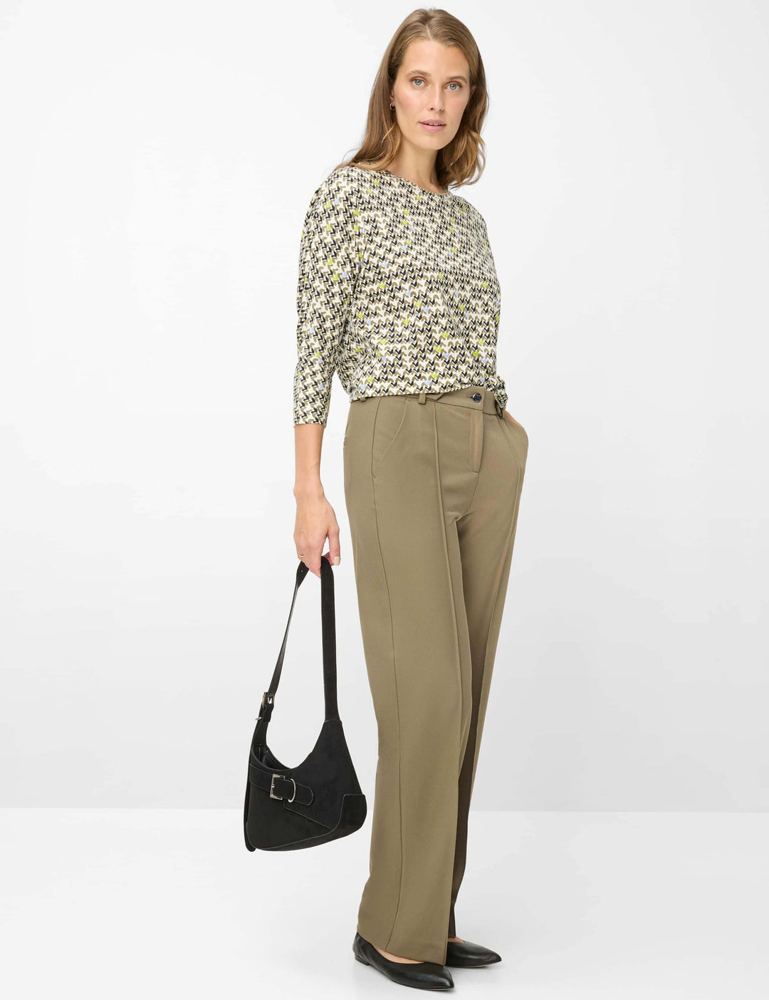 Femme portant le chandail imprimé graphique CHARLENE avec manches trois-quarts et encolure ronde, accessoirisé d'un sac noir.