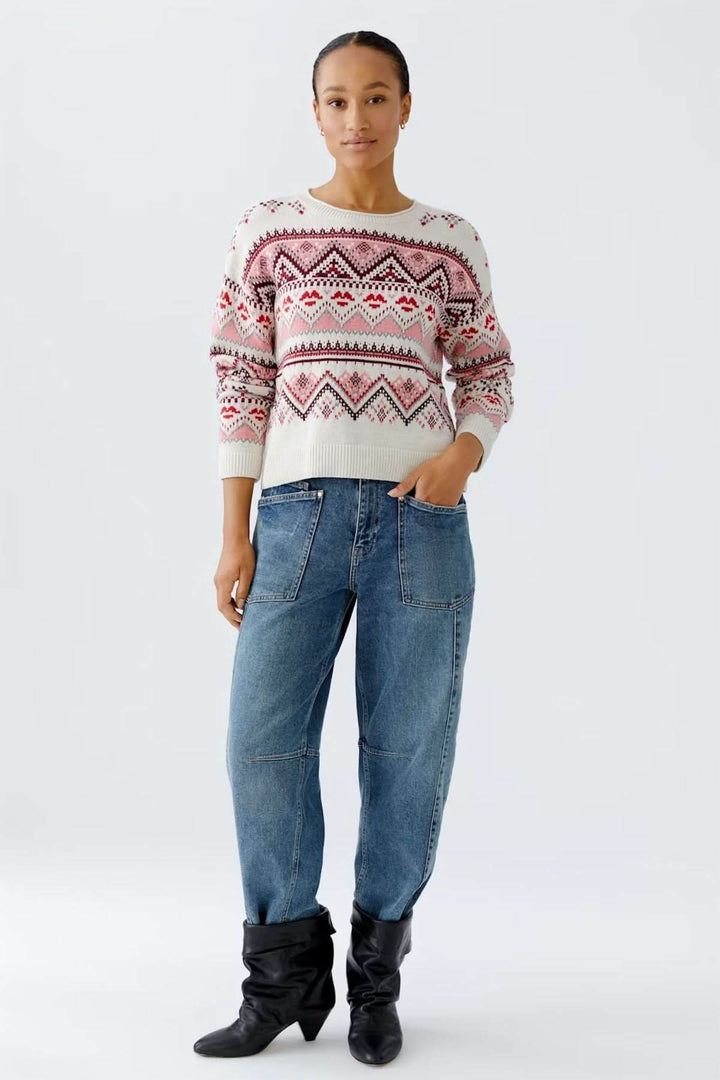 Femme portant un chandail jacquard à motifs géométriques avec jean et bottes, style décontracté pour hiver. Décris moi le produit.