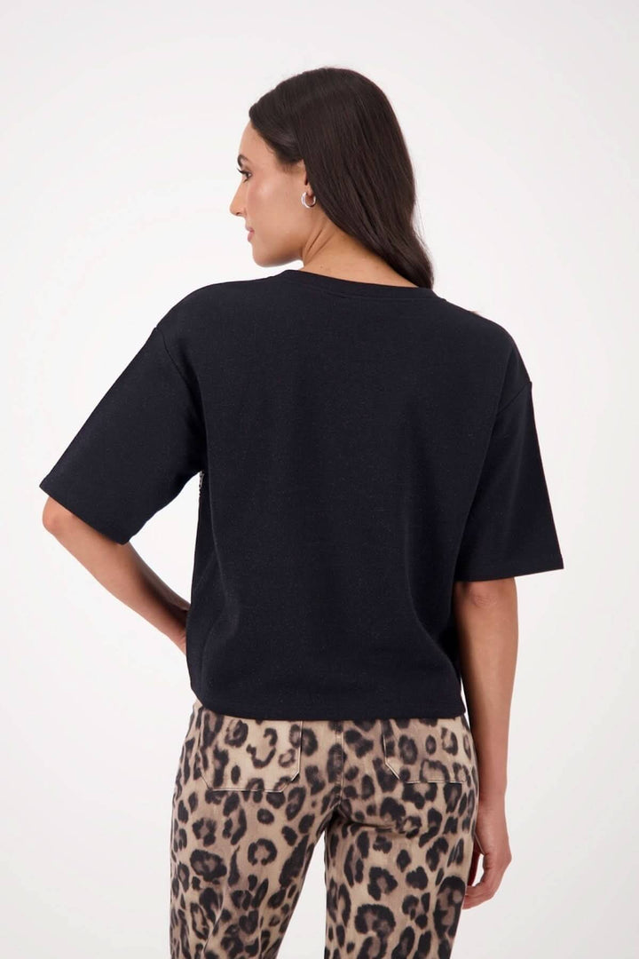 Chandail à manches courtes noir avec appliqués de paillettes, porté avec un pantalon léopard.