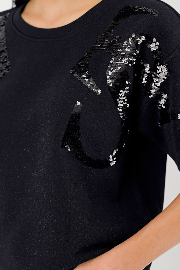 Chandail à manches courtes en maille noire avec appliqués de paillettes ton sur ton, design abstrait et chic.