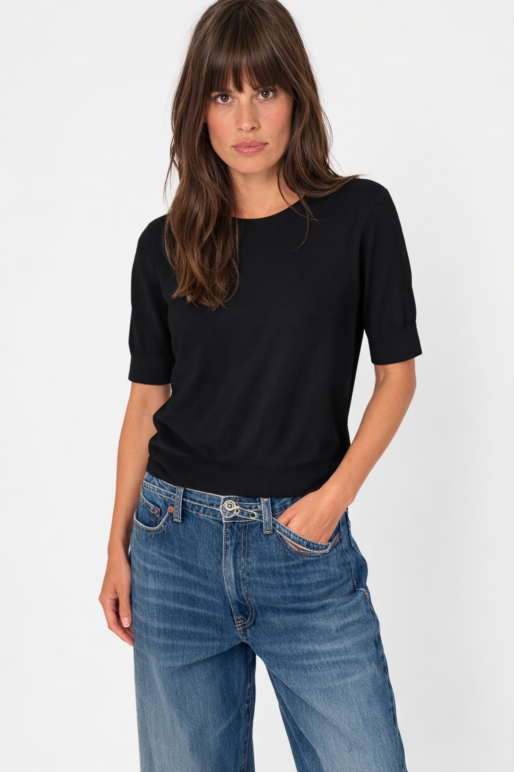 Femme portant un chandail à manches courtes noir avec jeans, silhouette élégante et confortable pour le quotidien.