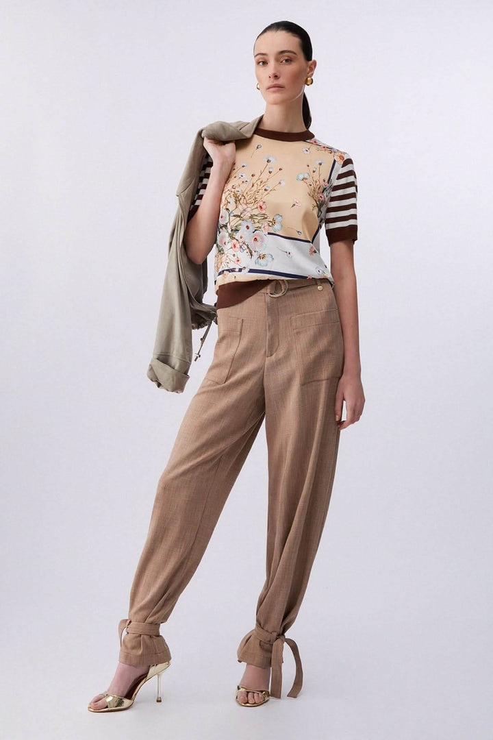 Femme portant un chandail à manches courtes avec motifs contrastés et un pantalon beige, mode moderne et élégante.