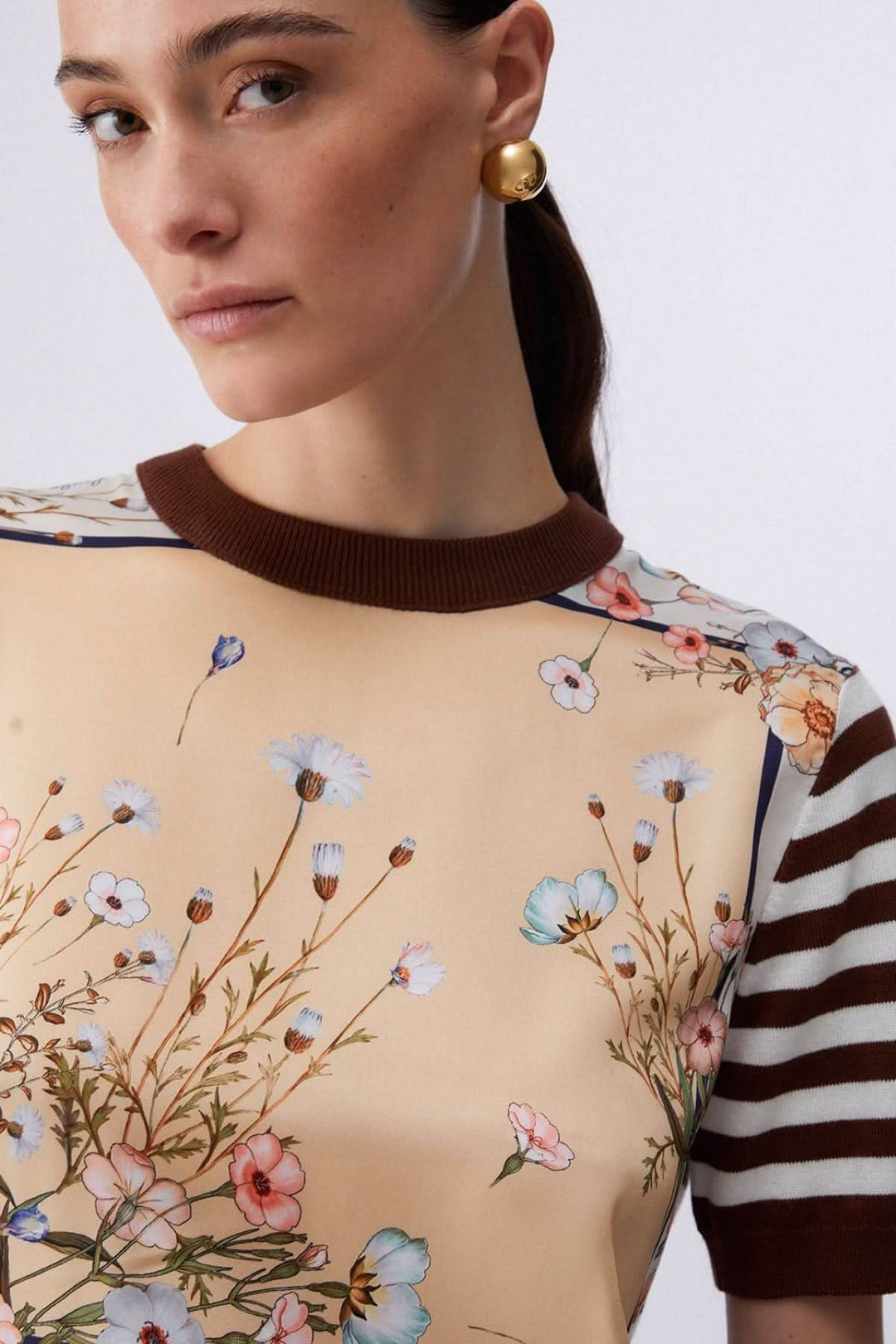 Femme portant un chandail à manches courtes avec motifs contrastés et rayures, style moderne et raffiné.