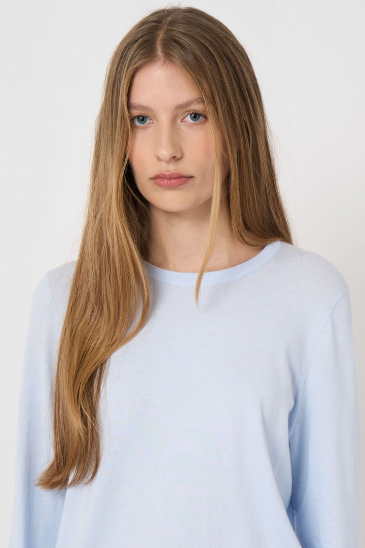 Chandail à manches longues en tissu doux avec encolure ronde et coupe droite, porté par une femme, idéal pour un look quotidien élégant.