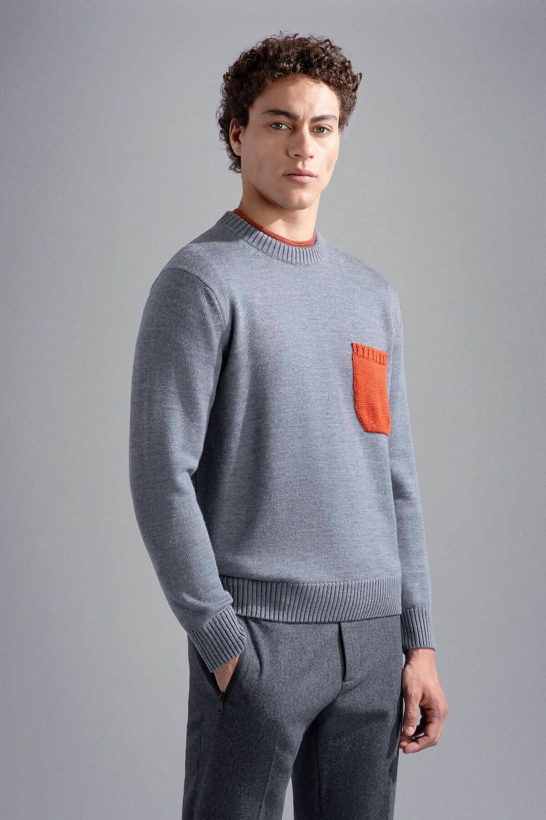 Pull moderne gris clair avec poche orange contrastante, col rond et bords-côtes.