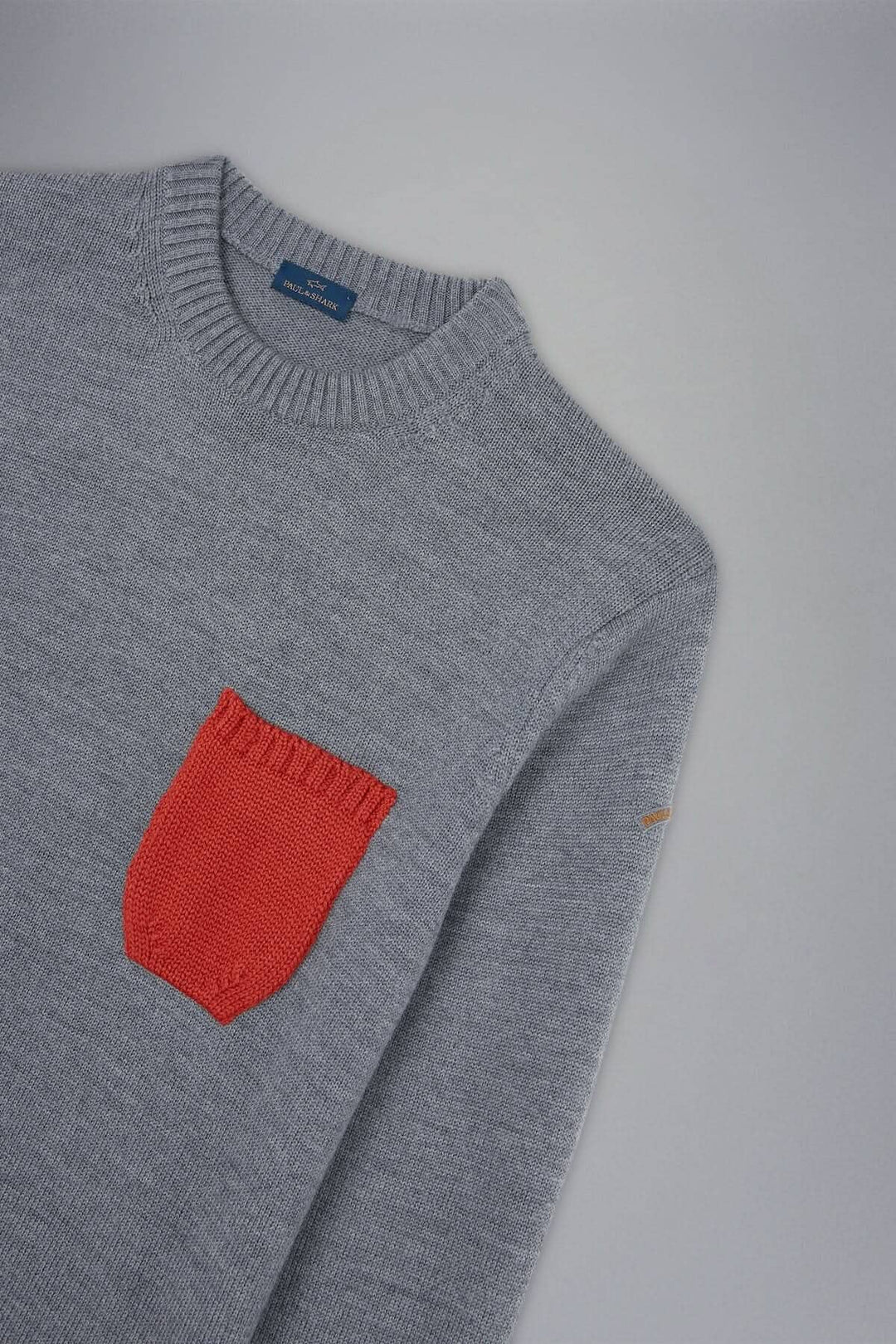 Pull gris clair avec poche orange contrastante, col rond classique et bords-côtes.