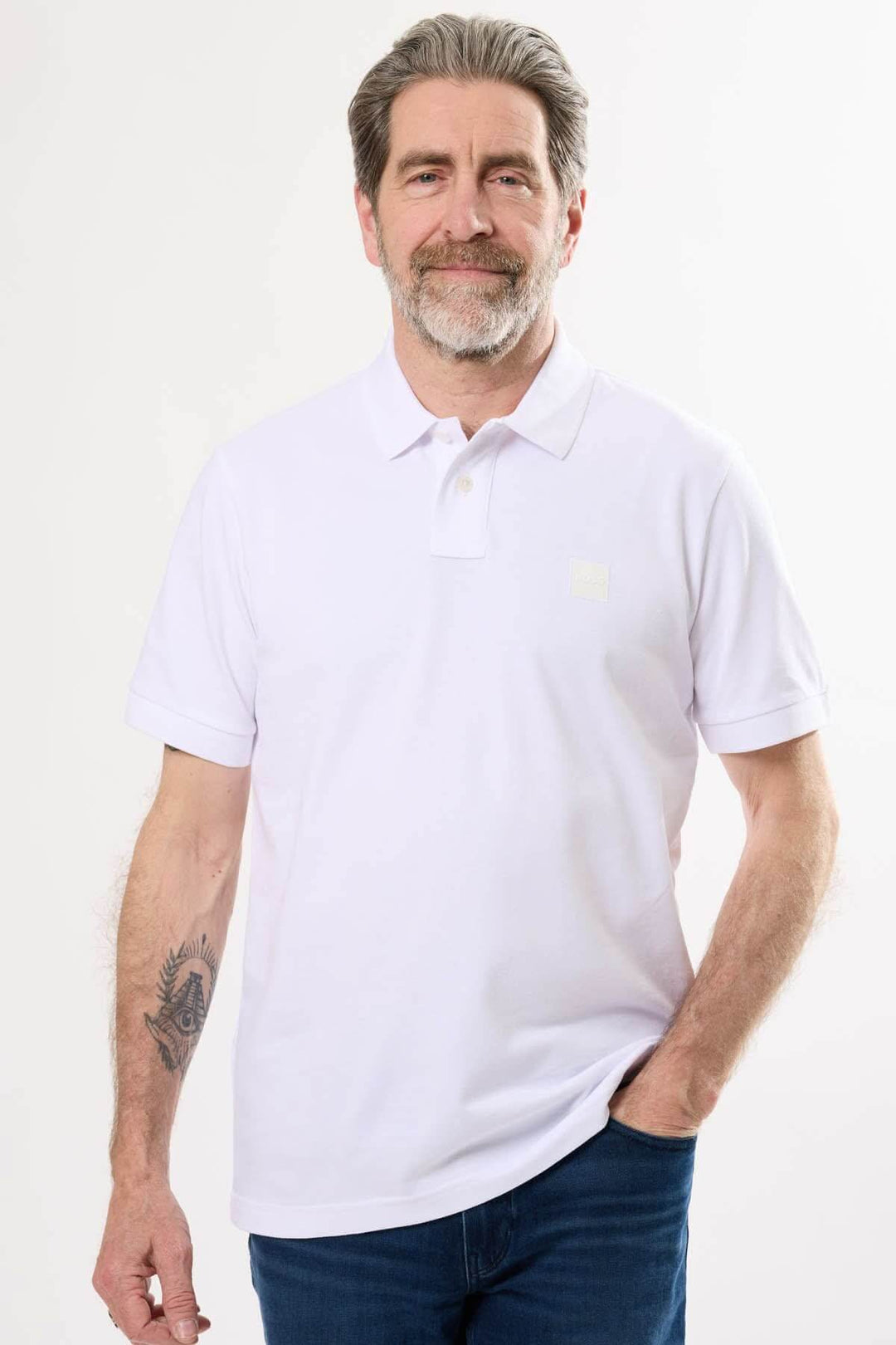 Homme portant un polo blanc à logo Boss, col polo, manches courtes, style casual-chic.