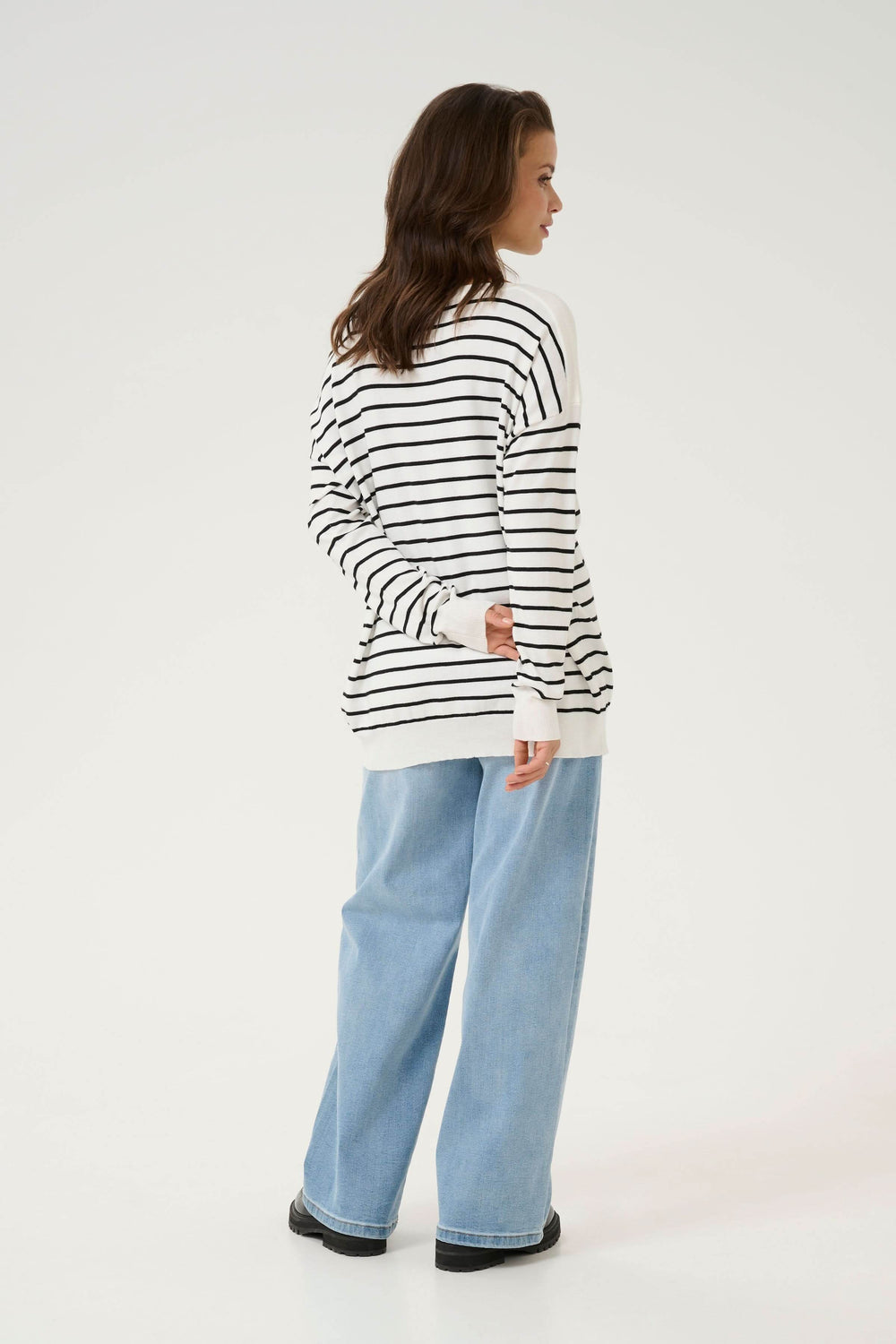 Chandail rayé décontracté avec encolure dégagée et manches longues, porté avec pantalon large en denim.