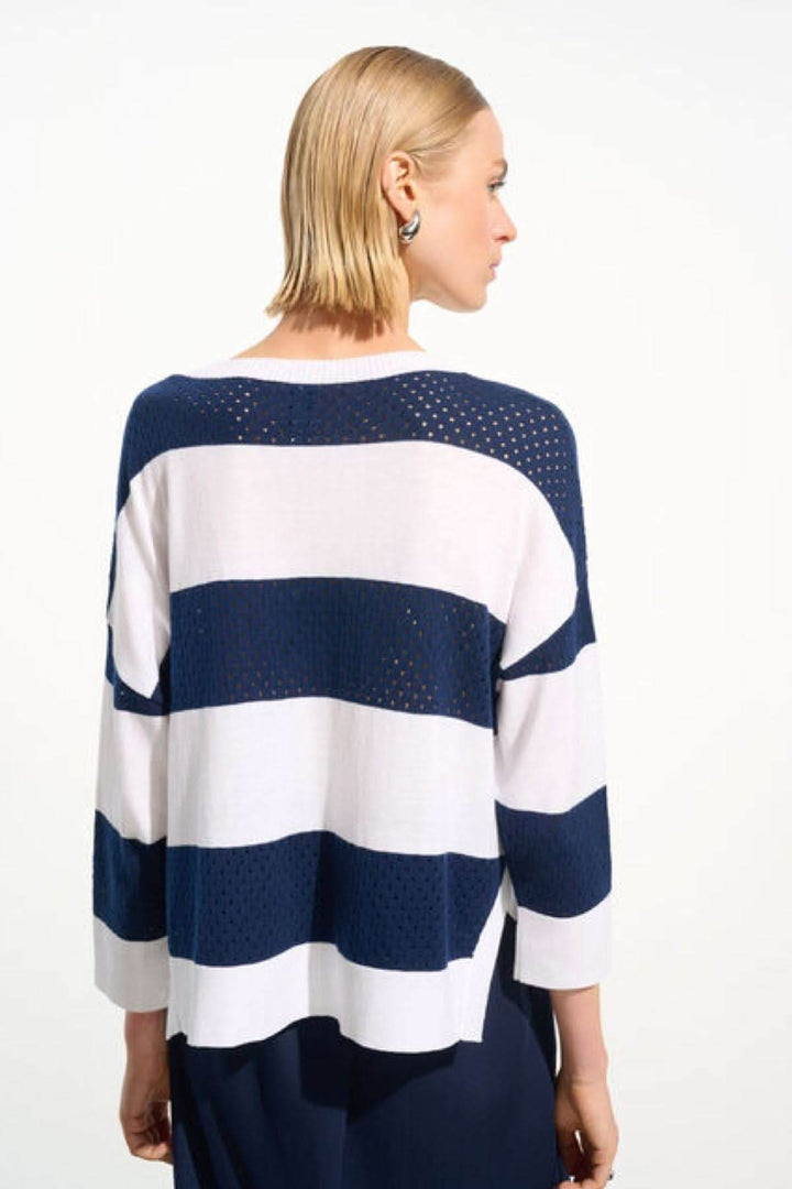 Femme portant un chandail rayé ajouré bleu et blanc, coupe ample, encolure ronde, parfait pour un look décontracté et chic.