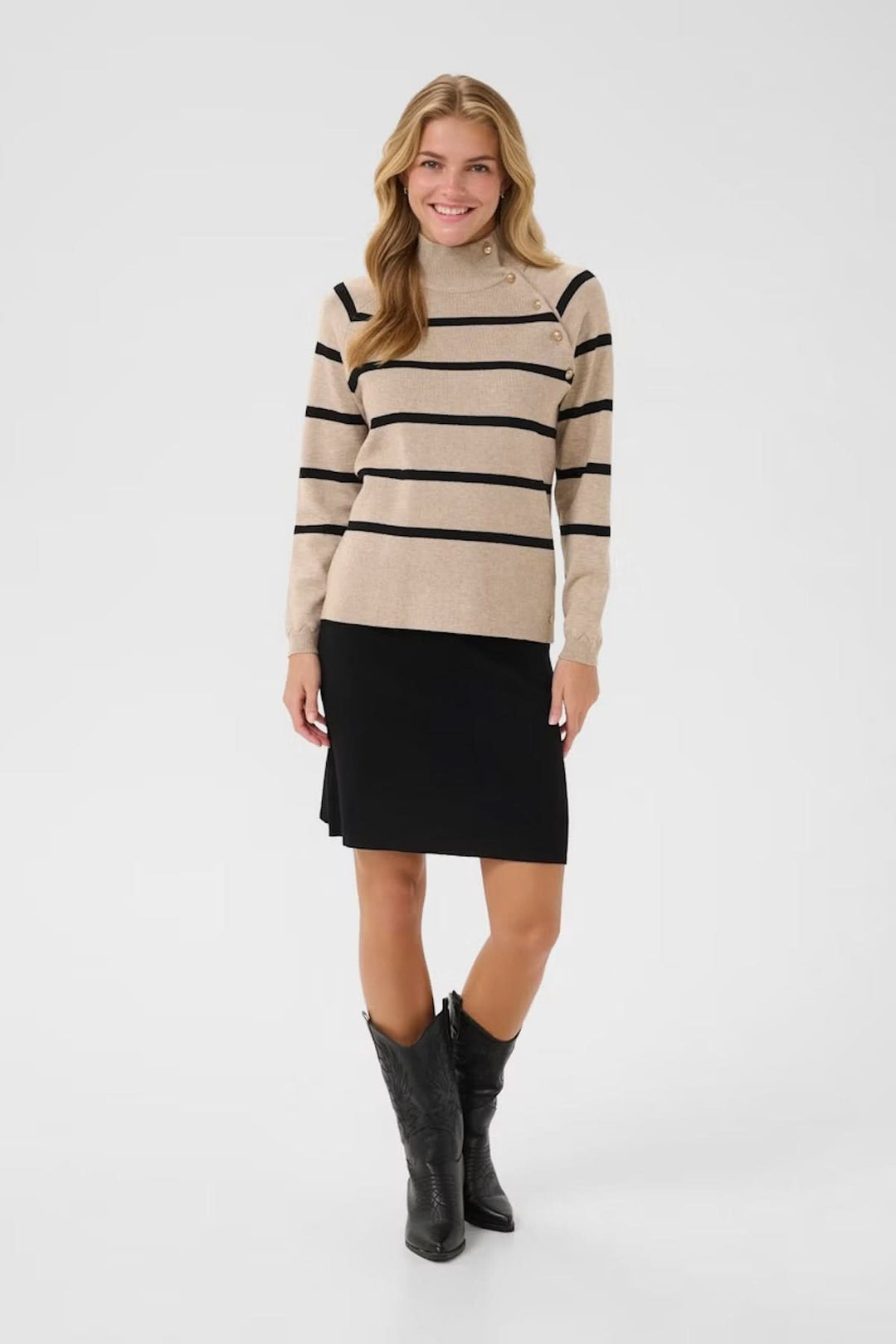 Chandail rayé à col montant beige et noir, porté avec une jupe noire, ideal pour un look chic et élégant.