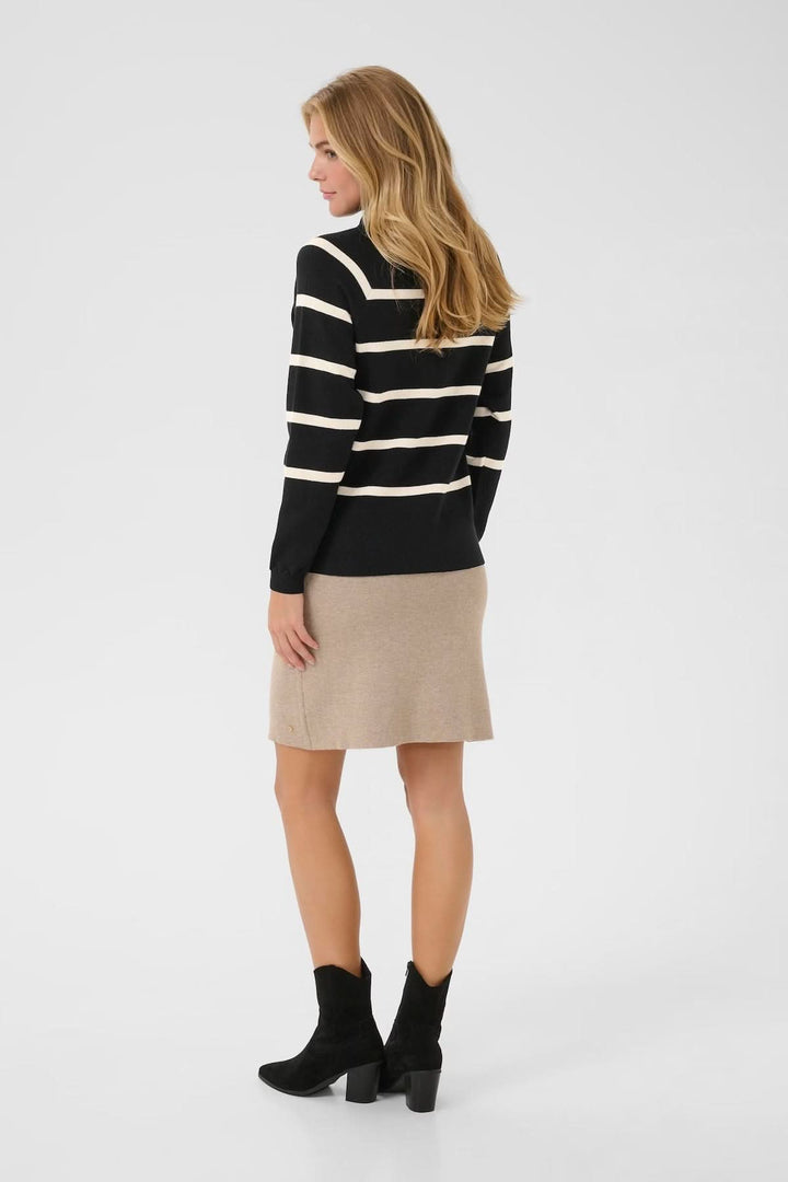 Chandail rayé à col montant noir et crème, porté avec une jupe beige et des bottines noires, vue arrière.