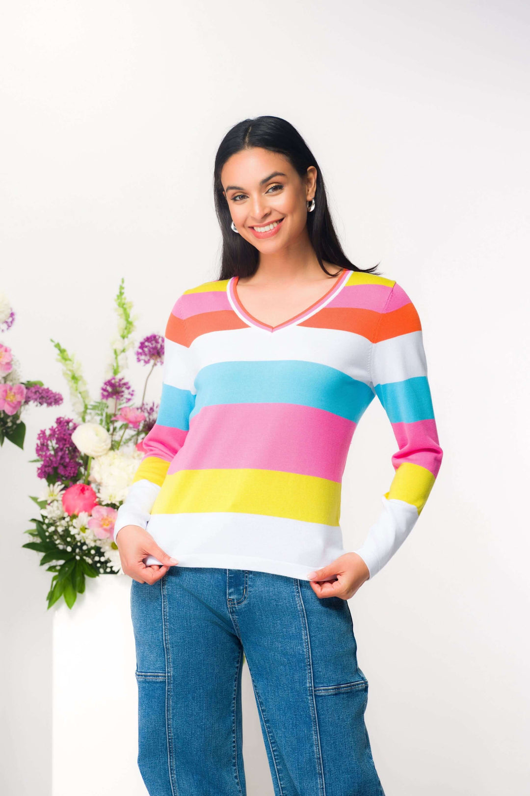 Femme portant un chandail à rayures colorées avec encolure en V, confortable et ajusté. Chandail à rayures pour style moderne et dynamique.