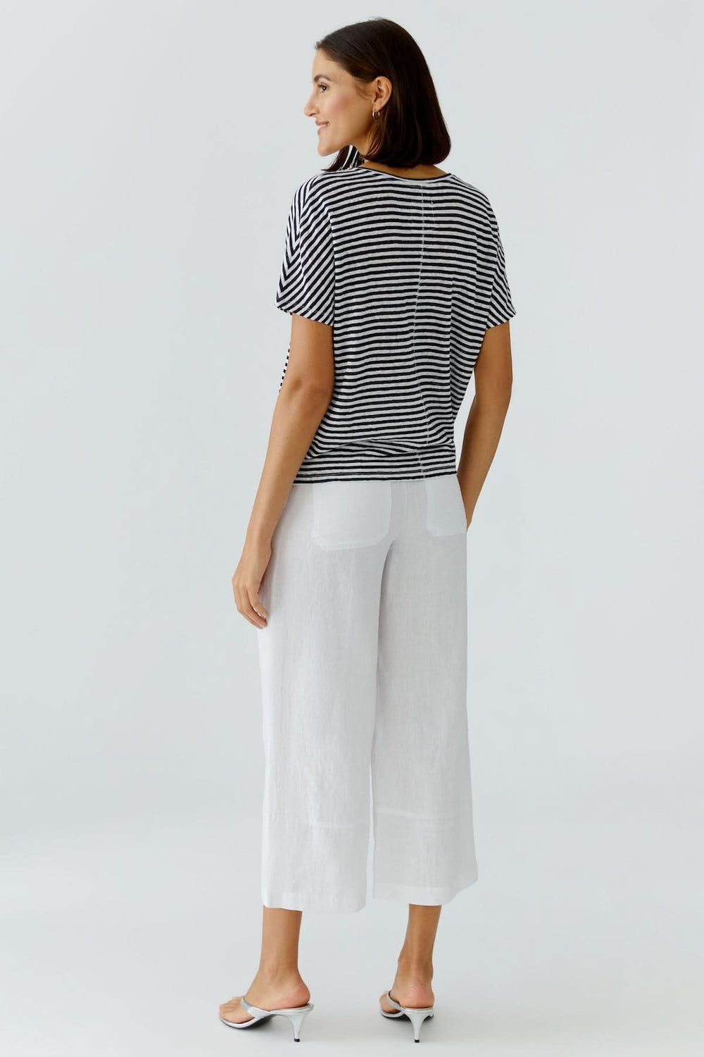 Femme portant un chandail à rayures col en v avec pantalon blanc, style décontracté élégant idéal pour le quotidien.