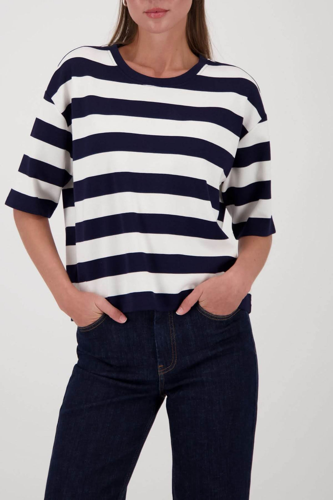 Femme portant un chandail à rayures col rond bleu et blanc avec manches courtes et coupe droite, style moderne et décontracté.