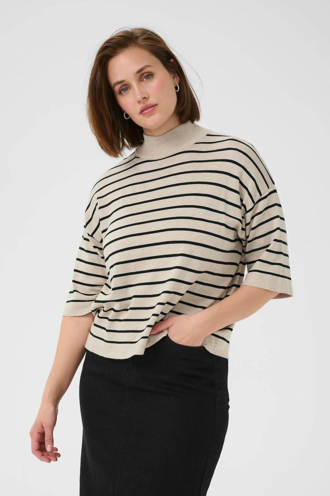 Chandail à rayures fines et col montant, coupe moderne et décontractée, porté par un modèle avec un jupe noire.