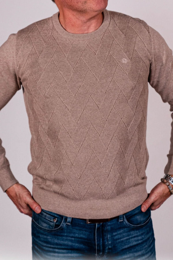 Chandail beige avec motif chevron, col rond, porté par un homme, associé à un jean. Élégant et confortable.