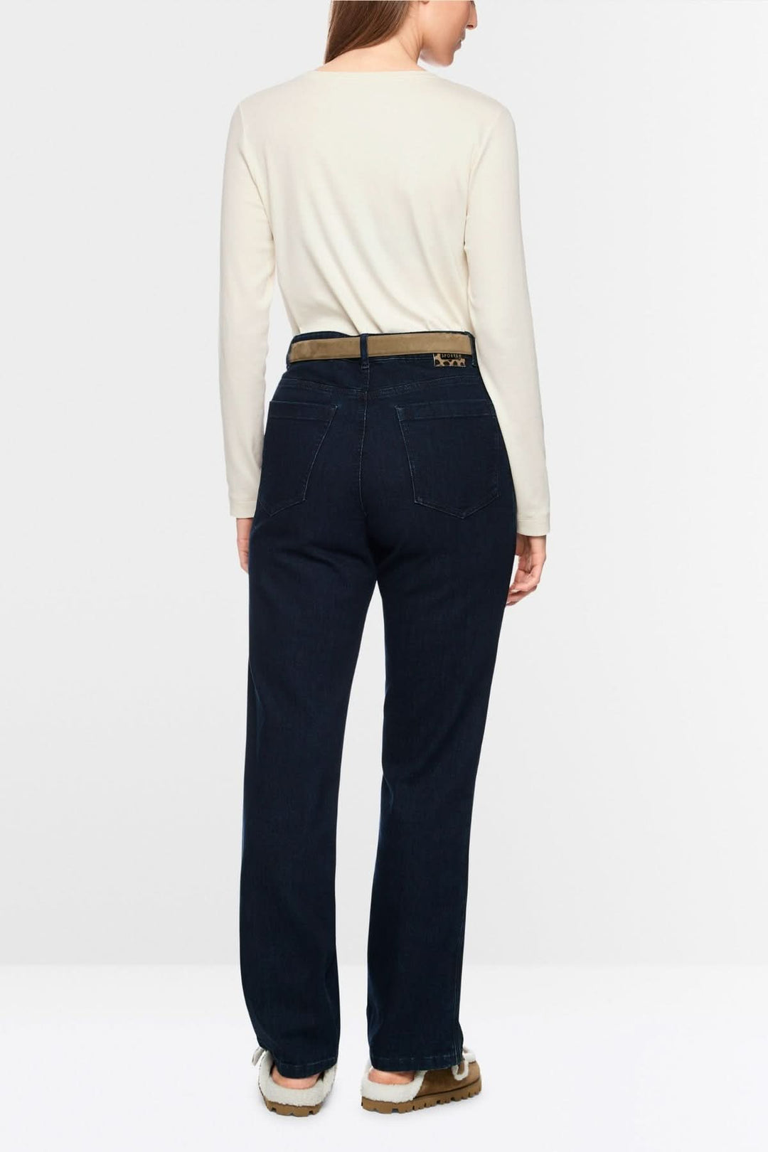 Femme portant un chandail unie à manches longues crème, assorti à un pantalon bleu foncé, vue arrière. Style minimaliste et chic.
