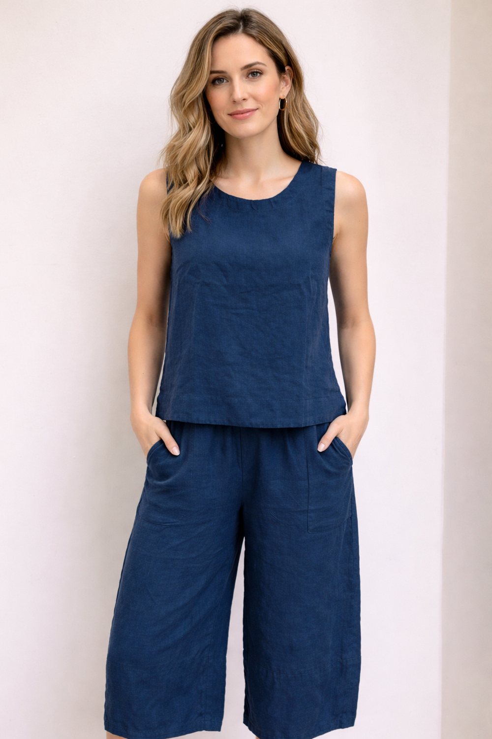 Femme portant un pantalon ample en lin à taille élastique, coupe décontractée avec poches latérales, couleur bleu foncé.