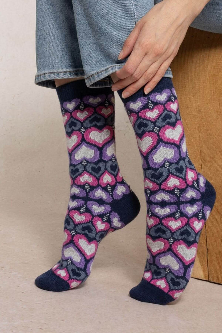 Chaussettes en tricot à motif avec cœurs multicolores, mi-mollet, sur fond beige, parfaites pour un look ludique et chic.