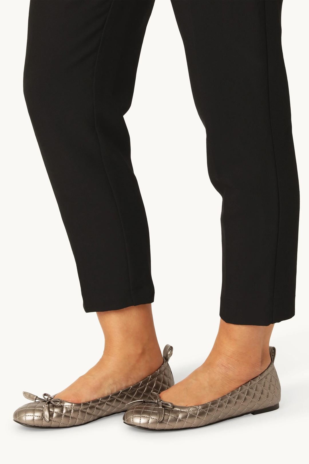 Chaussure ballerine Altura matelassée avec design élégant et noeud décoratif en fini texturé, portée avec un pantalon noir.