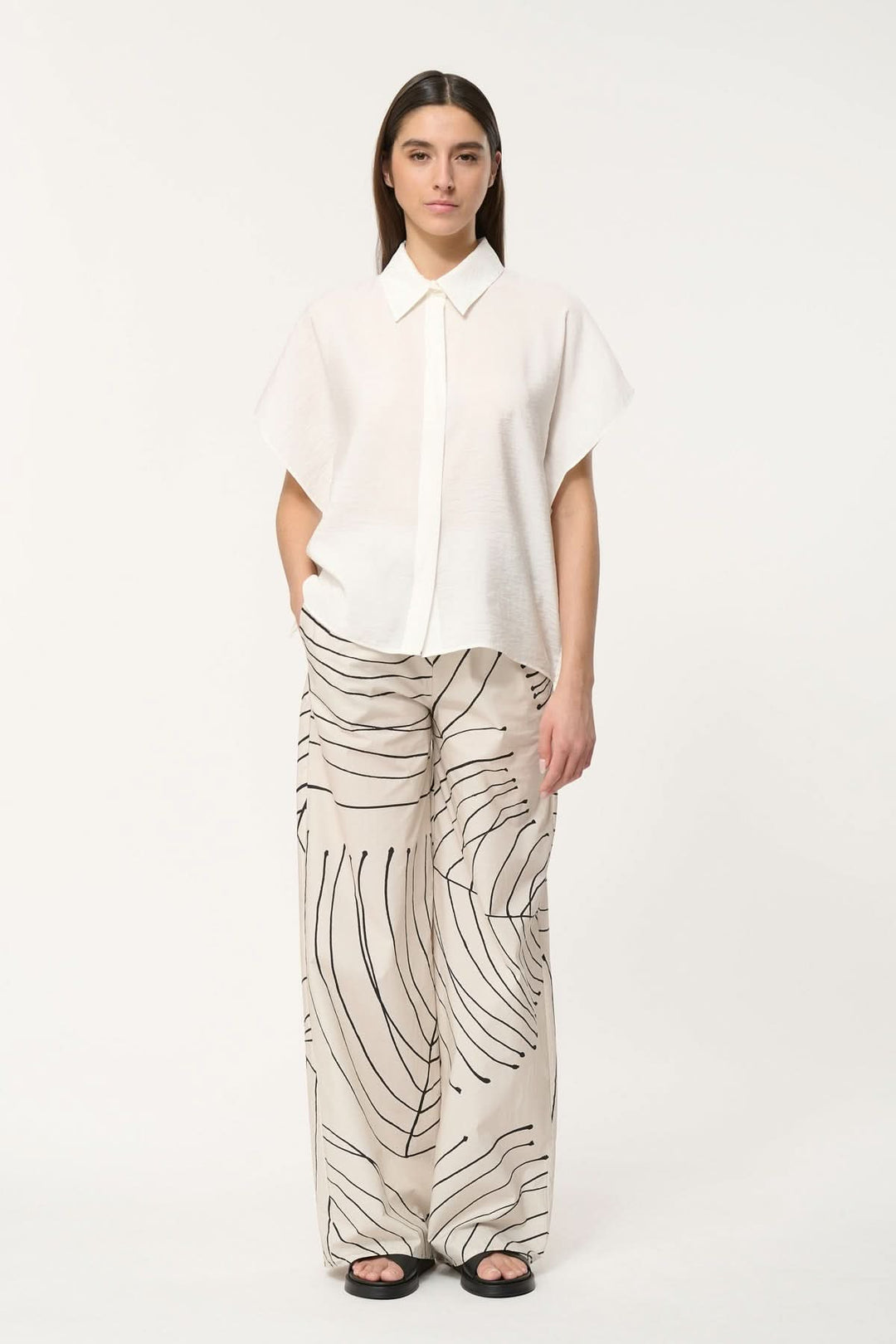 Femme portant une chemise légère à coupe ample et un pantalon à motifs modernes, style décontracté.
