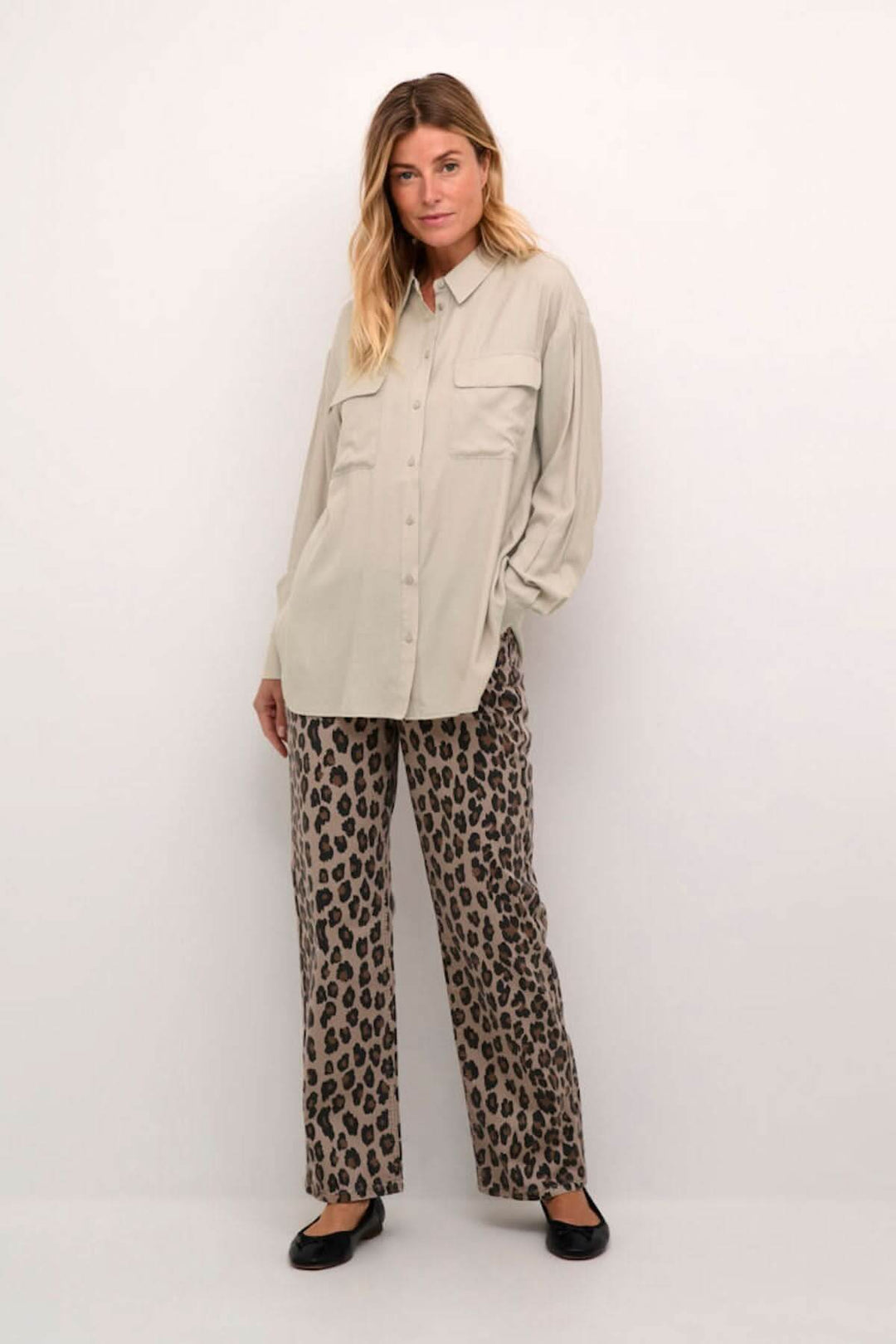 Chemise moderne beige avec poches, manches amples, pantalon léopard, look décontracté et soigné.