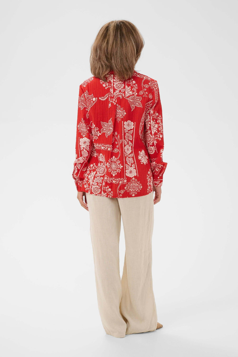 Vue arrière de la Chemise Gianna imprimée à manches longues en rouge, portée avec un pantalon beige, montrant le motif décoratif.