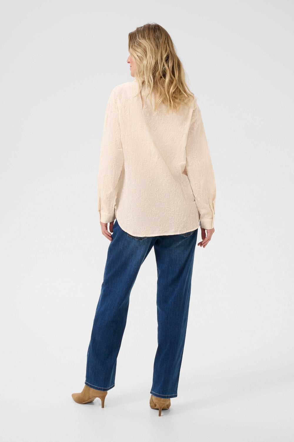 Femme vue de dos portant une chemise élégante et un pantalon en denim, style raffiné et décontracté.