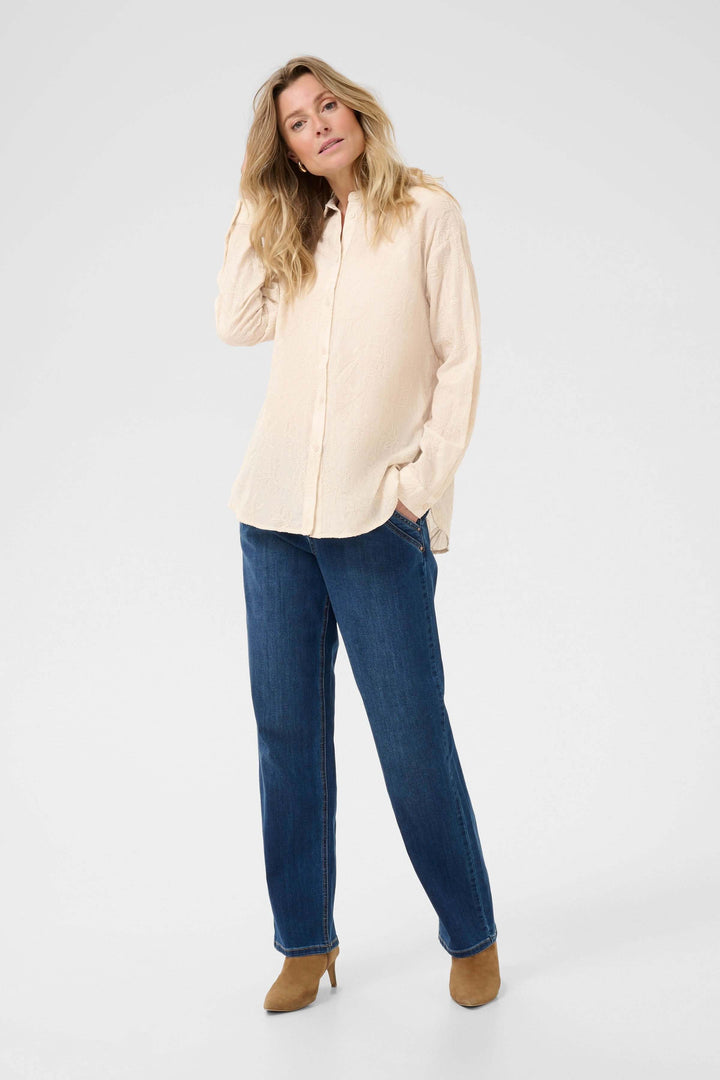 Chemise élégante à broderies florales, portée avec un jeans, pour un look romantique et raffiné.