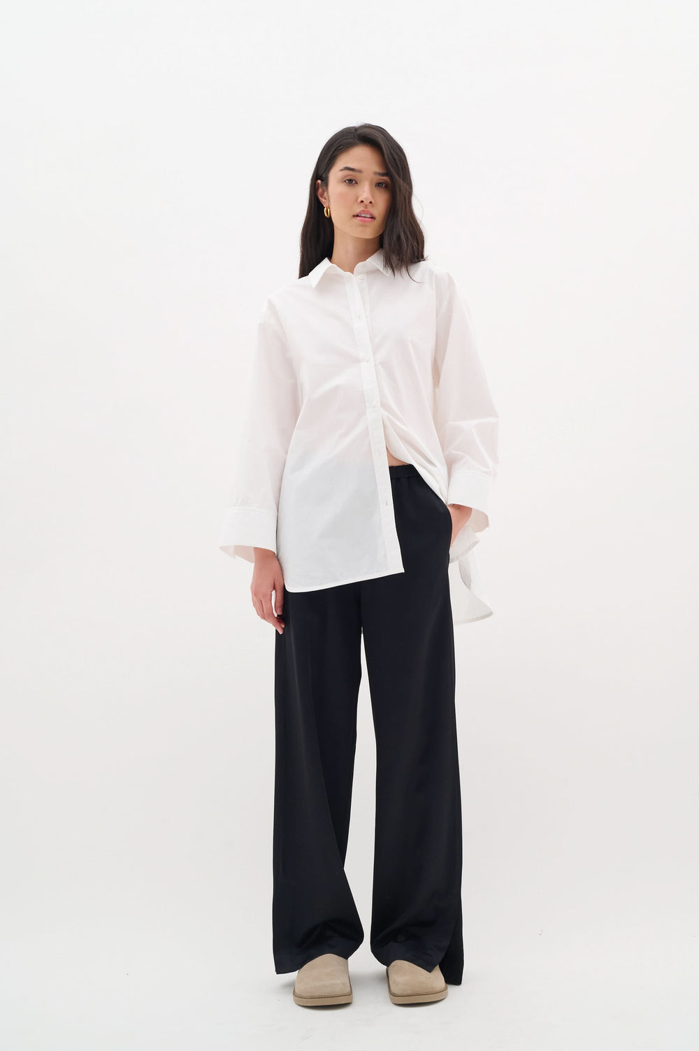 Chemise Merlissa oversize blanche avec pantalons noirs, style chic minimaliste et confortable.