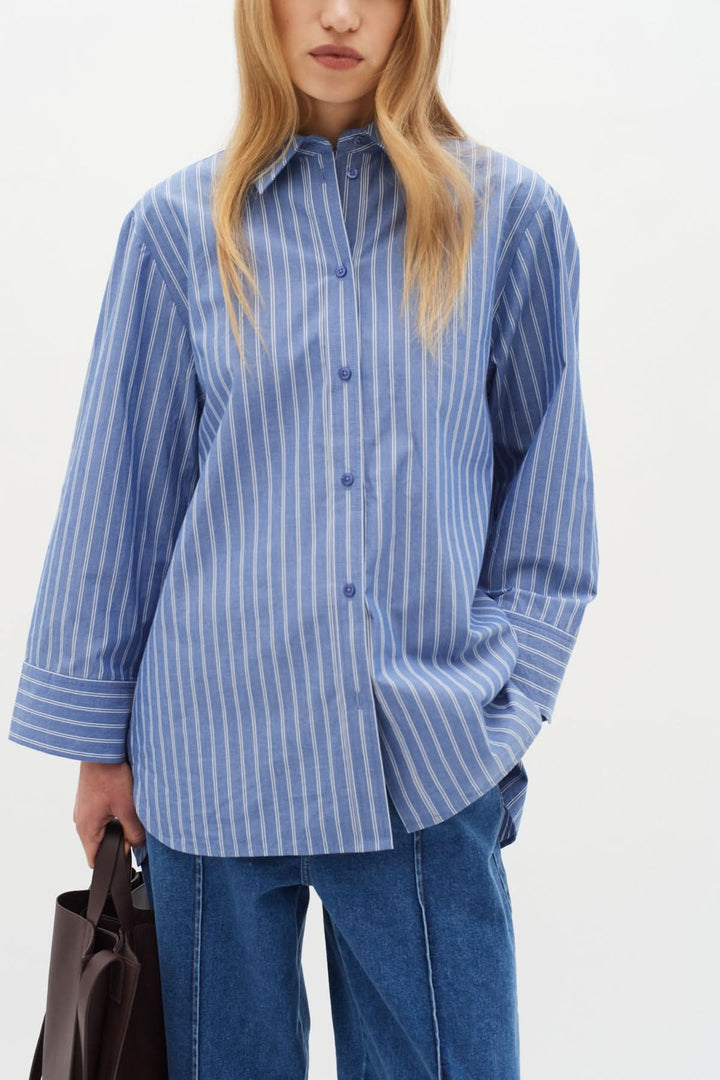 Chemise Merlissa bleu rayé, coupe oversize, chic minimaliste, col classique, confortable en coton.