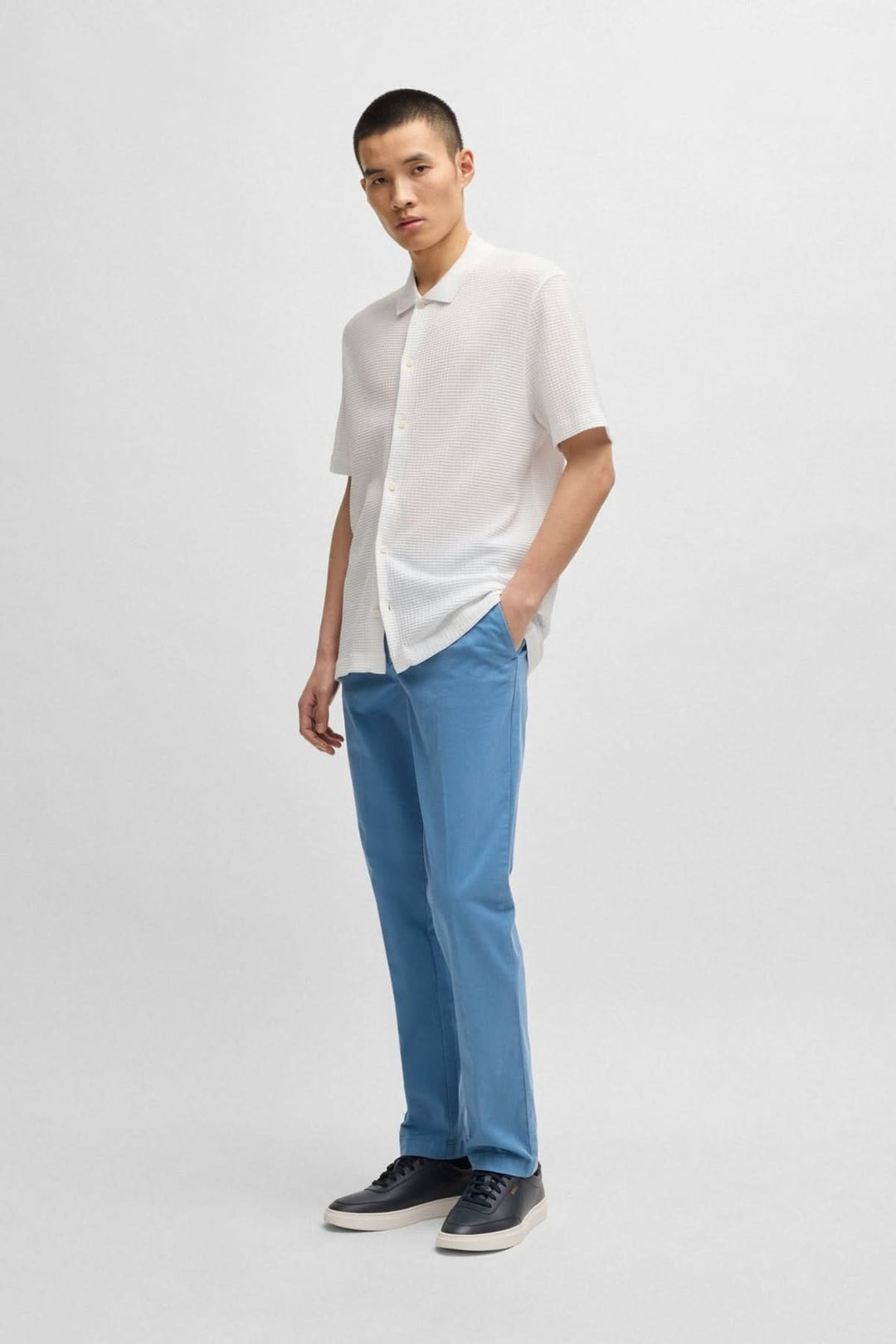 Homme portant une chemise légère en coton et un pantalon bleu, alliant style casual et élégance.