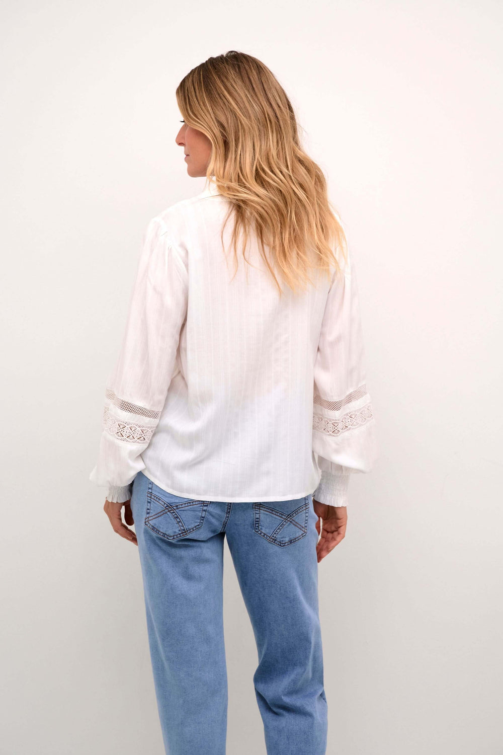 Chemise Paula à l'arrière, avec manches bouffantes et détails en dentelle, portée avec un jean.