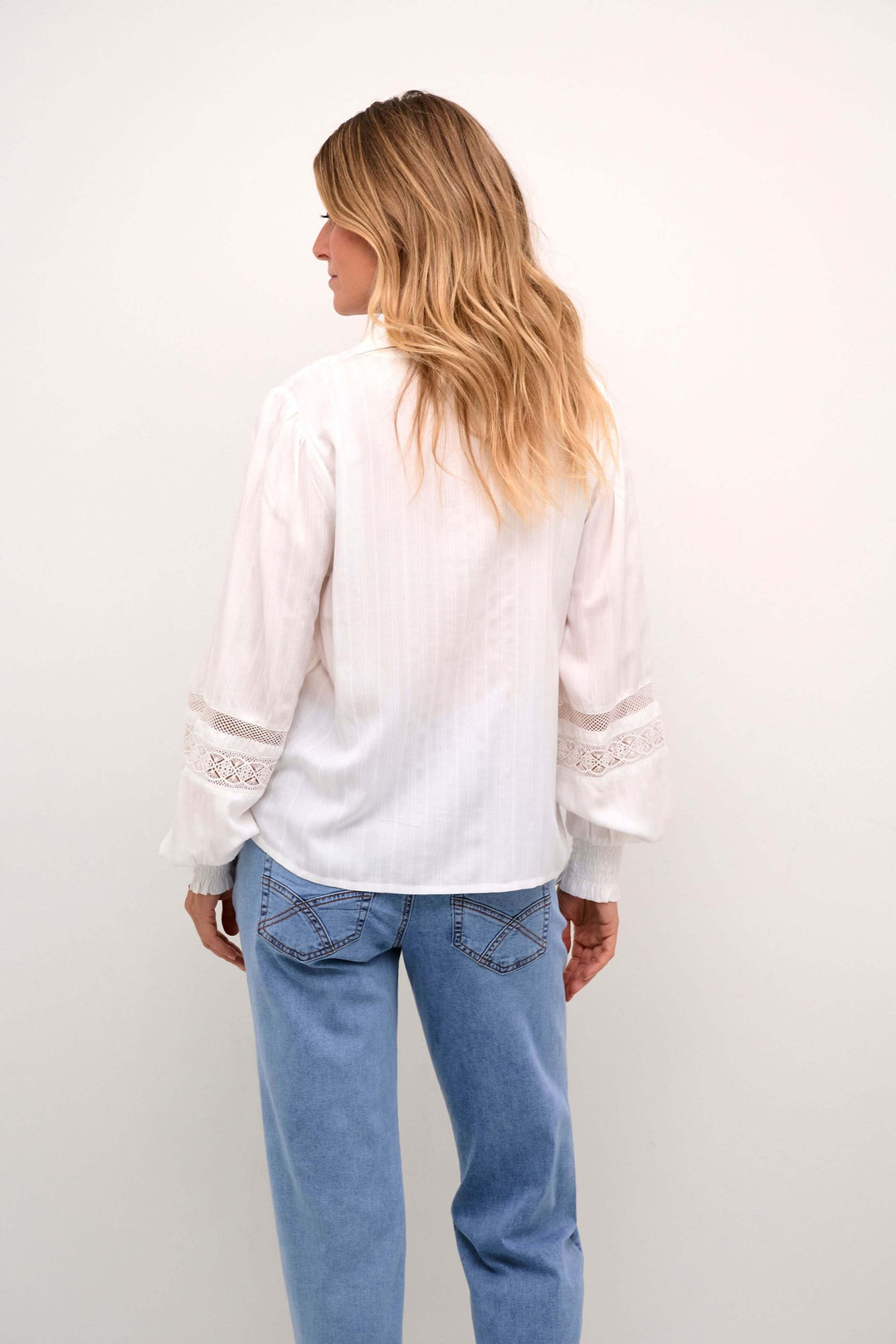 Chemise Paula à l'arrière, avec manches bouffantes et détails en dentelle, portée avec un jean.