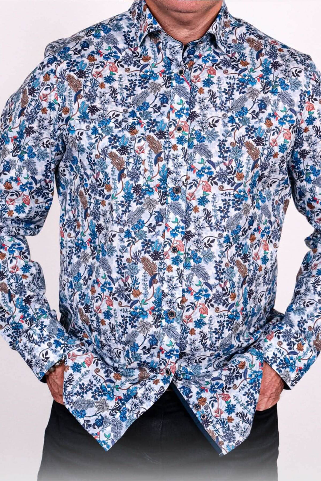 Chemise bleu à motifs floraux vibrants en bleu, orange et blanc, avec col pointu et poches, parfaite pour un look tendance.