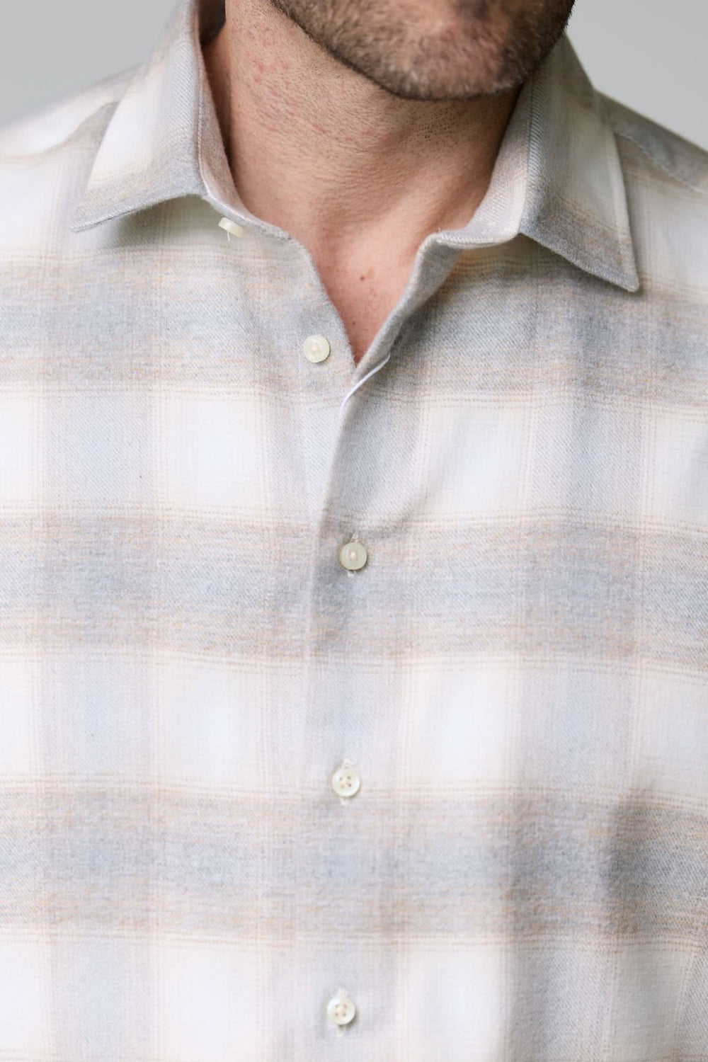 Chemise à carreaux doux en flanelle avec motif subtil, col classique, et boutons nacrés sur fond gris clair.