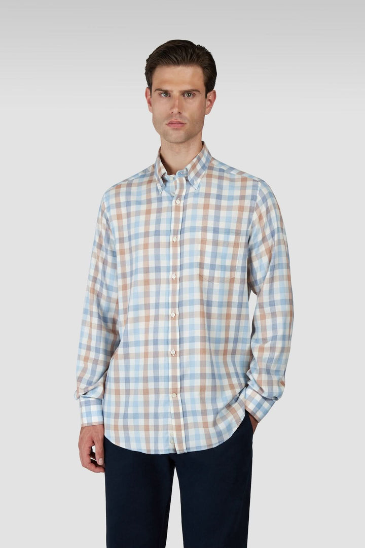 Homme portant une chemise à carreaux manches longues col boutonné, tenue moderne et polyvalente avec motif classique.