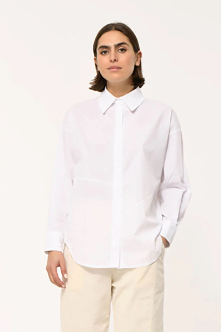 Femme portant une chemise classique à coupe droite, col pointu et manches longues, style moderne et soigné pour un look décontracté chic.