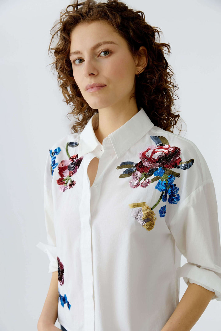 Chemise coupe moderne avec broderies florales; élégante et féminine, idéale pour un look soigné ou décontracté.