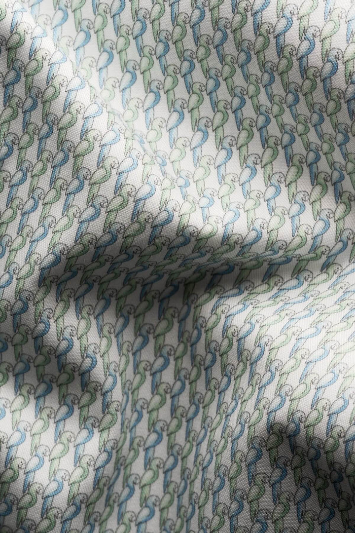 Tissu en coton avec imprimé perroquet en tons de vert pâle et bleu, idéal pour chemises élégantes.