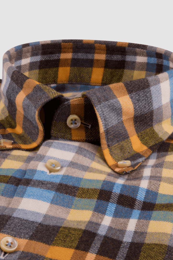 Chemise en flanelle à carreaux avec col boutonné, couleurs bleu, jaune et marron, idéale pour les journées fraîches.